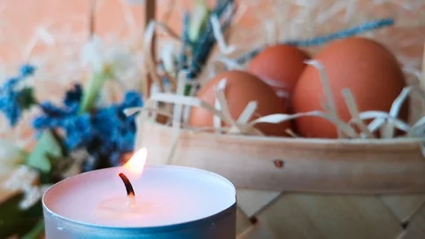 Tea light candle burns next to basket with eggs Stock Footage 104654316