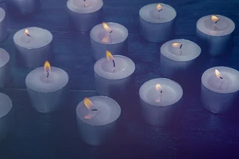 Tea light candles on a dark background, many lights in the dark 스톡 사진