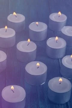 Tea light candles on a dark background, many lights in the dark Stock Photos