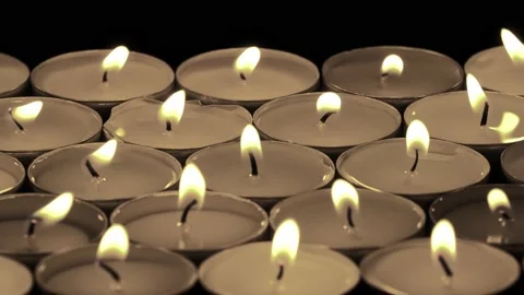 Tea-light candles lit, in light wind, on a black background. 스톡 동영상 169758844