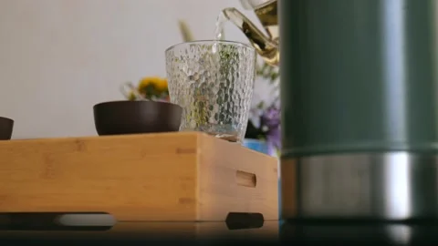A tea lover pours brewed white tea from a teapot into a special tea glassware Stock Footage 220342166