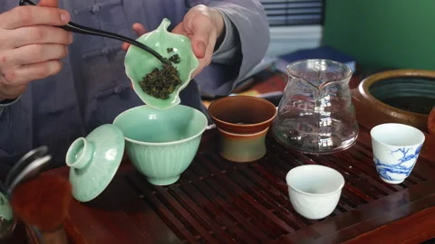 Tea master brewing tea putting large leaves from cha he to gaiwan using stick. Stock Footage 241012206