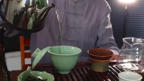 Tea master brews tea in gaiwan pours hot water from metal pot and closing lid. Stock Footage 241012830