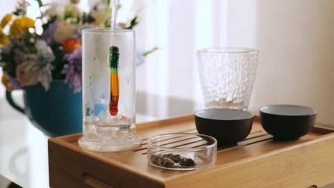 Tea master pours boiling water into a glass teapot to wash tea utensils Stock Footage 220341731