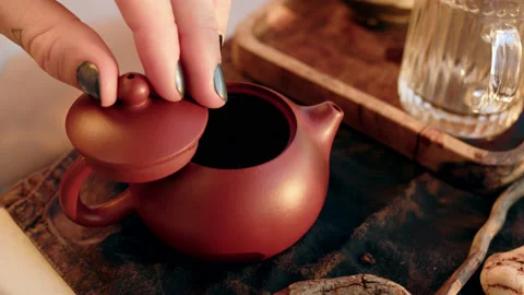 Tea master pours boiling water from chrome-plated thermos into brown clay small Stock Footage 223050693