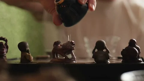 A tea master pours hot tea from a bowl over a tea figurine on a tea board. Stock Footage 220536969