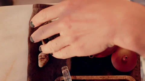 Tea master pours pu-erh tea leaves into ceramic clay teapot from bowl using Stock Footage 223052566