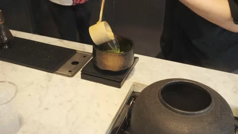 Tea master using wooden ladle to scoop hot water into a cup of green tea powder. Stock Footage 232233479