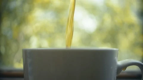 Tea or other liquid is casually poured into a cup close-up slow motion Stock Footage 155689363