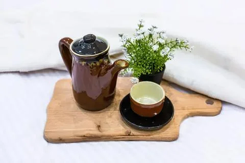 Tea pot and cup with a small green plant on wooden tray Stock Photos