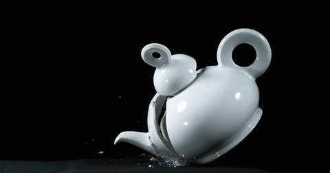 Tea-Pot falling and exploding on Black Background Stock Photos