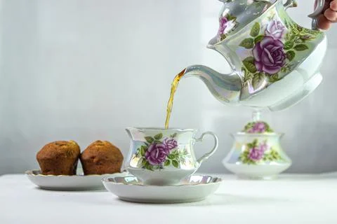 Tea is poured into a cup. A cup of tea on a white tablecloth. Light breakfast.  Stock Photos