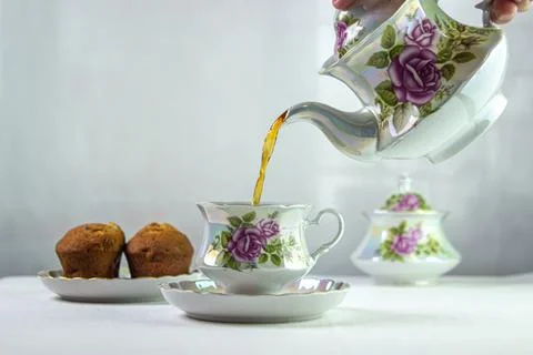 Tea is poured into a cup. A cup of tea on a white tablecloth. Light breakfast.  Stock Photos