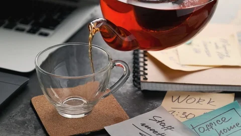 Tea is poured in a cup at the workplace.Office home concept Stock Footage 128579341