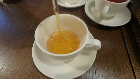 Tea is poured into a white cup and saucer. Stock Footage 163224146
