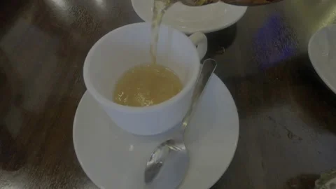 Tea is poured into a white cup and saucer. Stock Footage 164834553