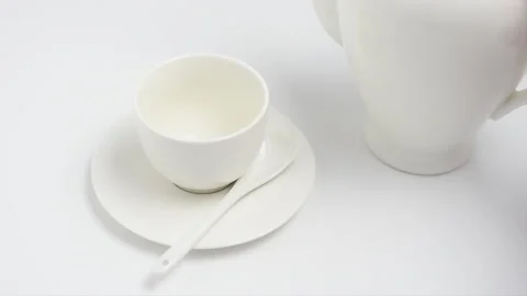 Tea is poured into a white Cup from a white teapot on a white background Stock Footage 135377880