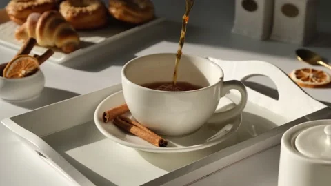 Tea is poured into a white mug or cup on a white, light background with fresh Stock Footage 197437847