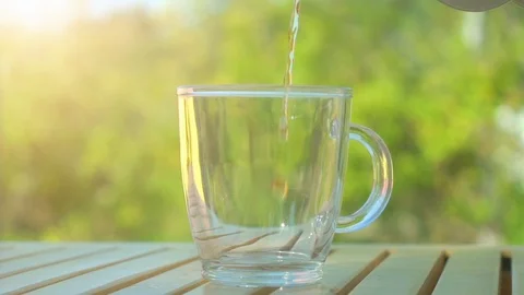Tea pouring into cup from teapot on green nature background with bright summer Stock Footage 116546070