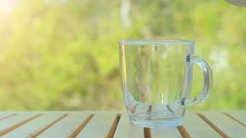 Tea pouring into cup from teapot on green nature background Stock Footage 116546102
