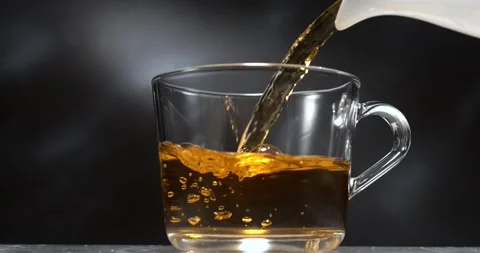 Tea pouring from teapot into transparent mug in slow motion Stock Footage 345977091