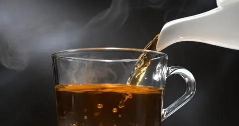 Tea pouring from teapot into transparent mug in slow motion Stock Footage 346226179