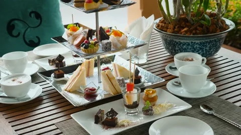 Tea set and coffee with assortment of pastries in outdoor cafe. Sweet breakfast Stock Footage 164112403