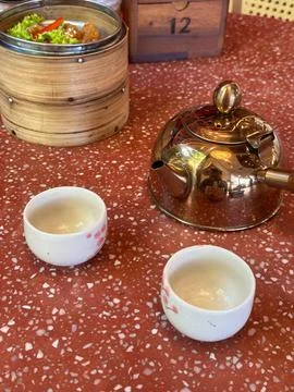 Tea set with pot and dim sum tray on red cement table Stock Photos