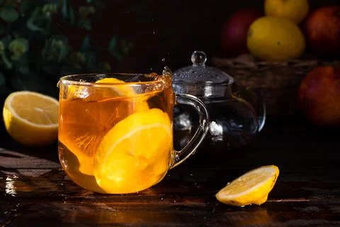 Tea is splashed out of a dissold mug with tea inside and pieces of lemon. dro Stock Photos