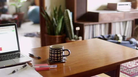 Tea steaming from a mug sitting on a coffee table with a laptop background Stock-Footage 134277979