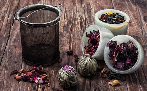 Tea strainer and different varieties of tea leaves on wooden background.The.. Stock Photos