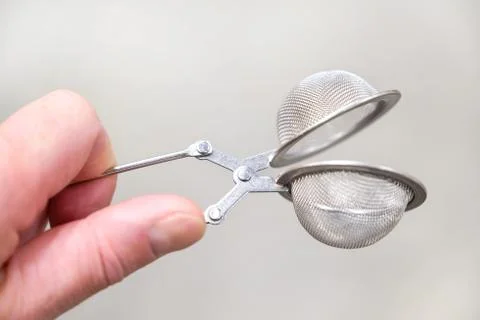 Tea strainer in hand close-up on a light background Stock Photos