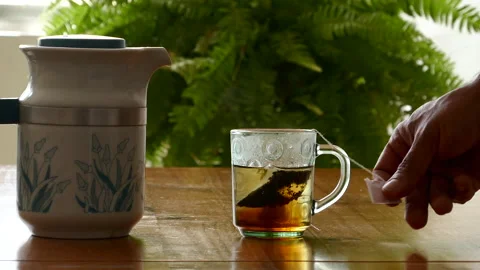 Tea on the table, man holds tea bag and stirs inside the cup Stock Footage 230464362