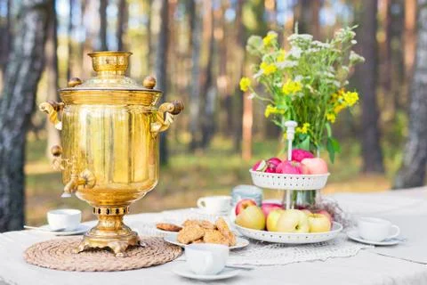 Tea table setting with samovar, apples, sweets outdoors 스톡 사진