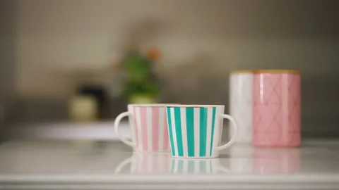 Tea table setting. Two mugs and utensils for tea and sugar stand on a white Vidéo 173555394