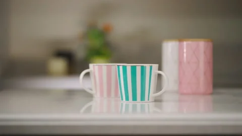 Tea table setting. A white mug with pink stripes and a white mug with tiffany Vidéo 173554684