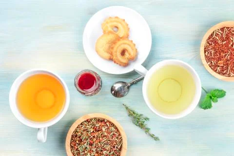 Tea tasting. Various cups of tea and loose dry tea leaves with cookies, jam, and Stock Photos