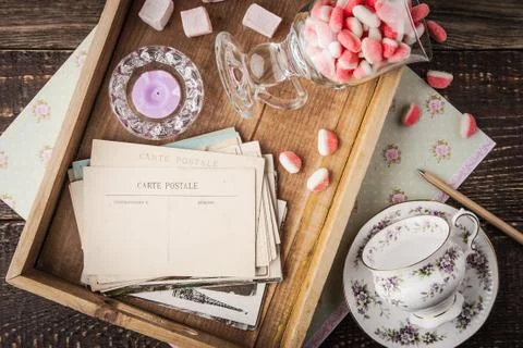 Tea things with sweets and postcards on the wooden tray top view Stock Photos