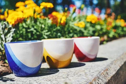 Tea time. Coffee break. Blue yellow red cups on marble in blooming garden Stock Photos