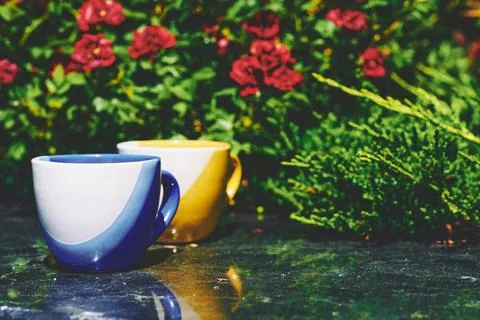Tea time. Coffee break. Blue yellow cups on marble in blooming garden Stock Photos