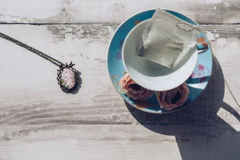 Tea time concept with tea bag inide porcelain teacup and vintage pendant Stock Photos