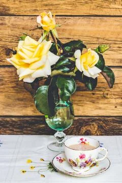 Tea Time: delicate cup of tea and yelow roses on wooden background Stock Photos