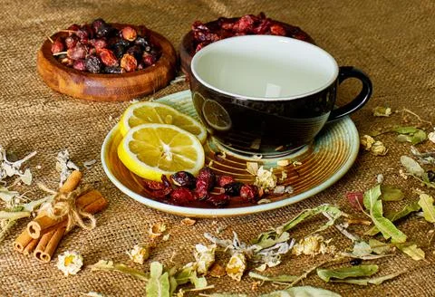 Tea Time: Empty black ceramic cup on the table, with herbs and dried fruits.. Stock-Fotos