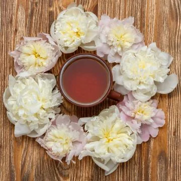 Tea time. Flat lay over wooden background with peonies and a cup of tea Stock Photos