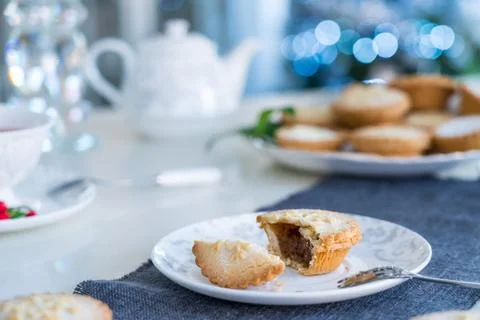 Tea time table setting with broken Mince Pie with filling on white plate. Tra Stock Photos