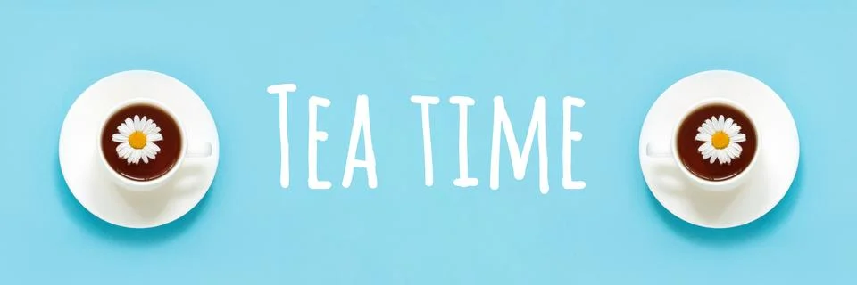 Tea time text and two white cup of tea with chamomile on dish saucer, blue ba Stock Photos