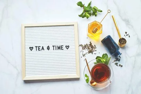 Tea time. White letter board with text on marble table with glass cup of tea  Stock Photos