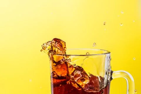 Tea in transparent mug on a yellow background splashed wiht ice Stock Photos