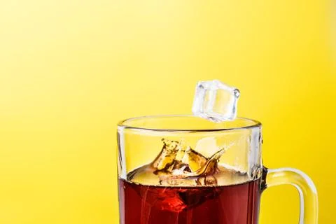 Tea in transparent mug on a yellow background splashed wiht ice Stock Photos