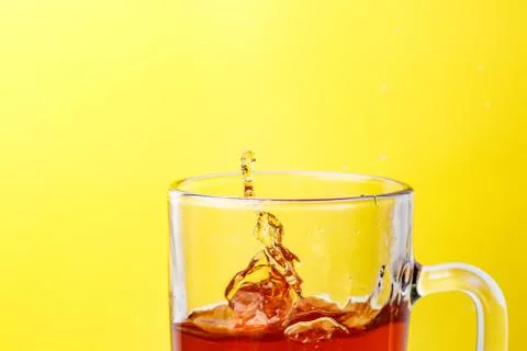 Tea in transparent mug on a yellow background splashed wiht ice Stock Photos